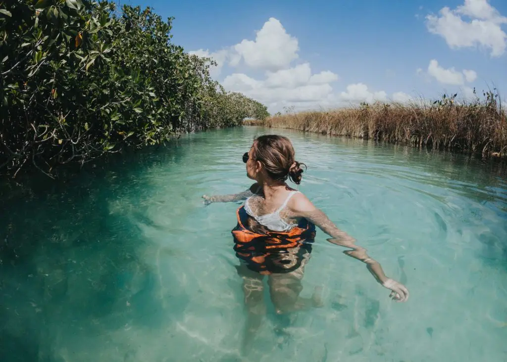 A woman wades through the natural lazy river at Muyil Lagoon near Tulum, which is a great add-on to this 3 day Cancun itinerary!
