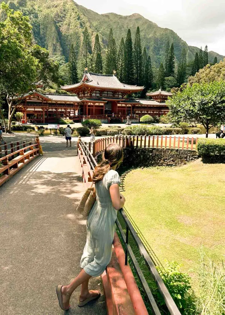 Woman standing on a bridge looking toward Byodo In Temple in Kaneohe, Oahu