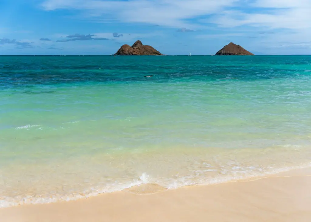 View of the Mokulua Islands with a snorkeler at Lanikai Beach, one of the best beaches in Kailua, Oahu