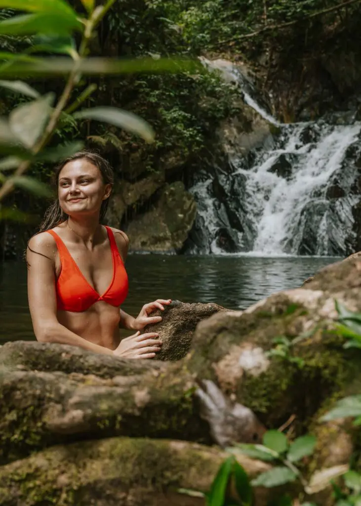 woman swimming below waterfall in belize central america