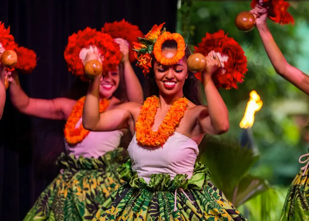 Women in traditional colorful clothing dancing at Toa Luau in Oahu, Hawaii