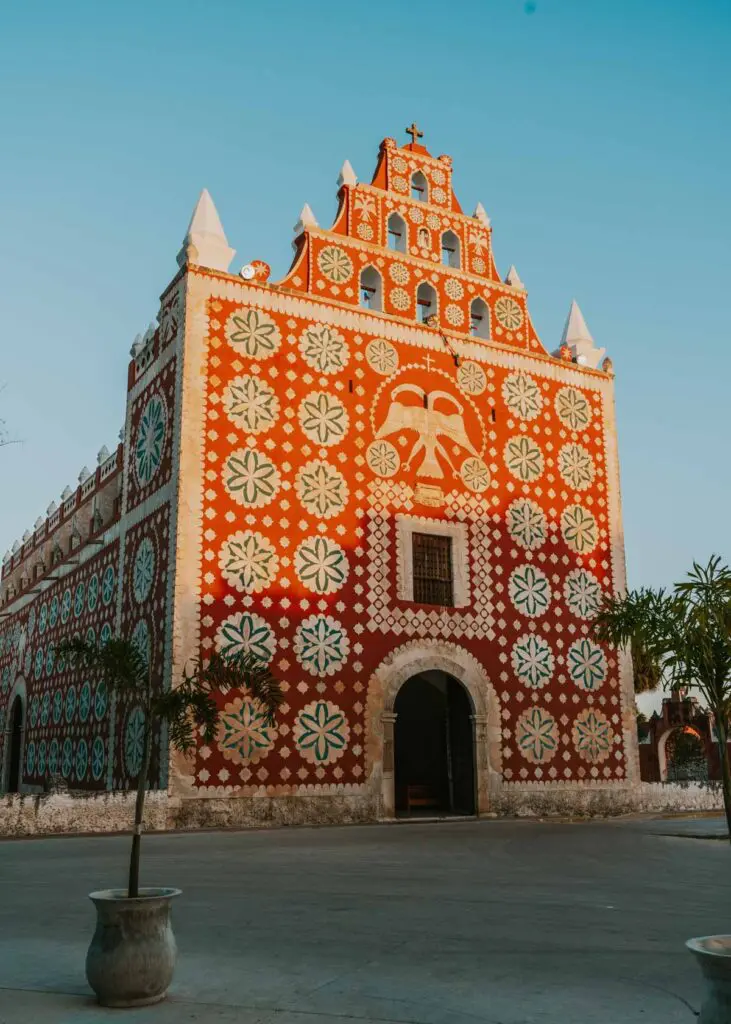 A historic building with an intricate red facade adorned with white floral and geometric patterns stands elegantly against the clear blue sky.
