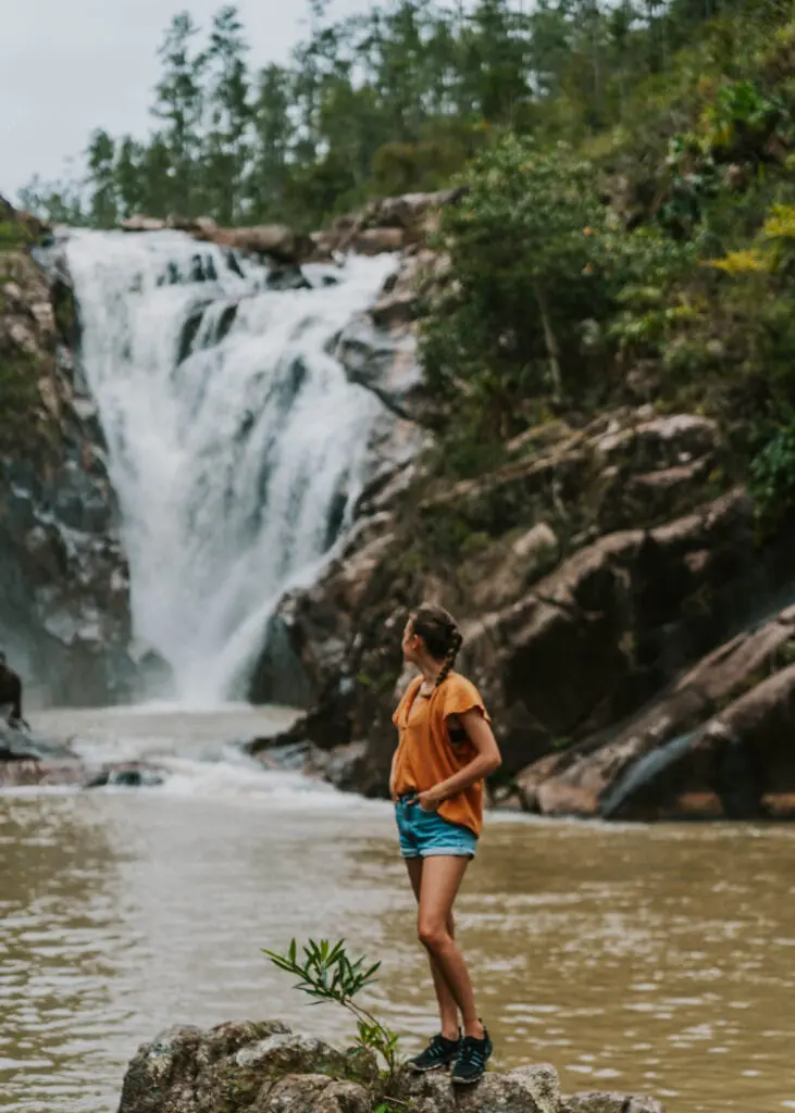 Woman standing on boulder in river in front of Big Rock Falls