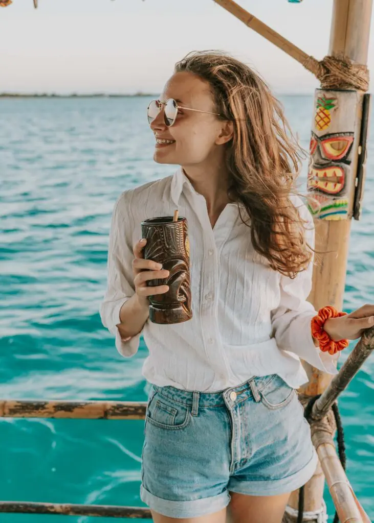woman standing on tiki boat in caye caulker belize with a drink