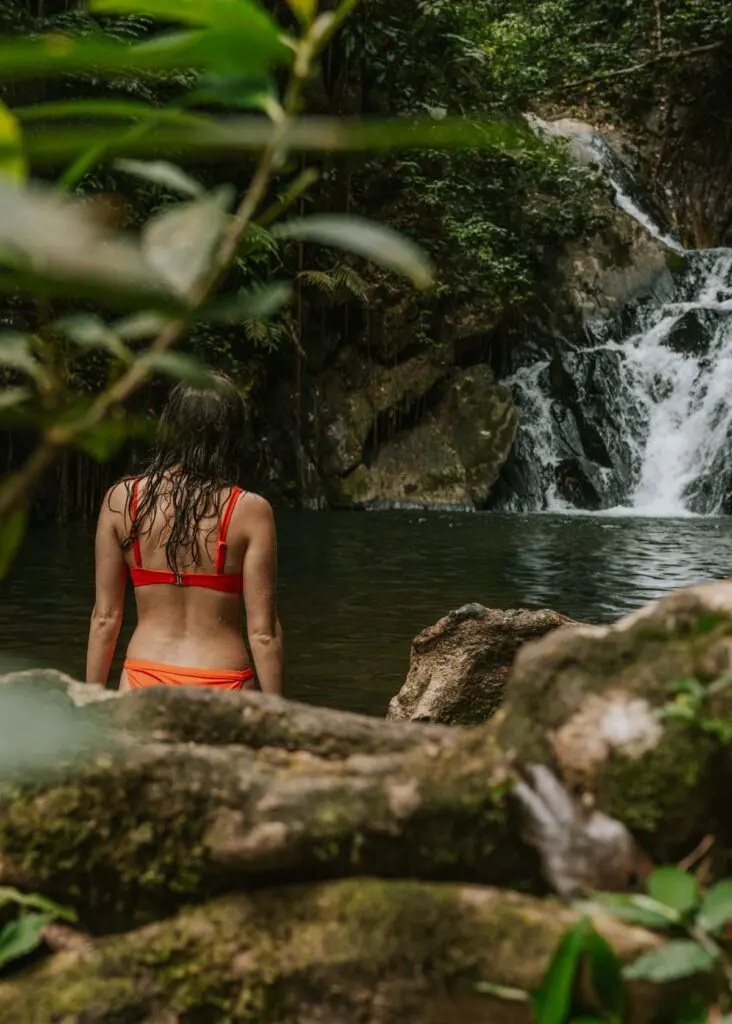 Woman wading beneath a waterfall on Belize's Hummingbird Highway