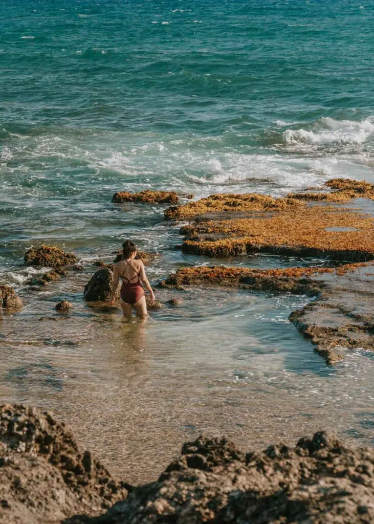 Woman wading in tidepool at Ka'ena Point Park in Oahu, Hawaii.