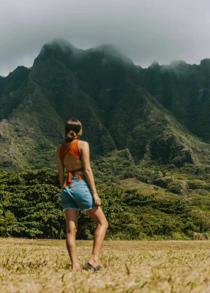 Woman standing in front of mountains on Oahu's eastern shore.