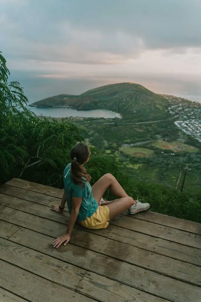 Woman at the top of Koko Crater, one of the best short Oahu hikes, with a view of Hanauma Bay as the sun sets.