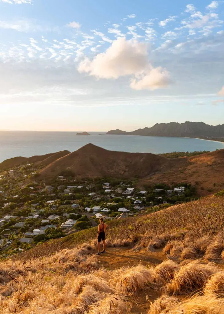 Woman standing at the top of the Lanikai Pillbox hike, overlooking Oahu's Lanikai neighborhood and bay