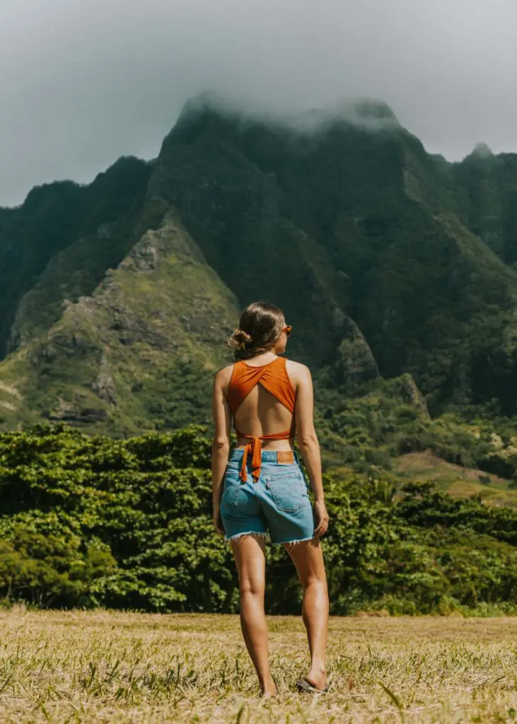 A woman standing in front of misty green mountains on Oahu's windward coast near Kualoa Ranch.