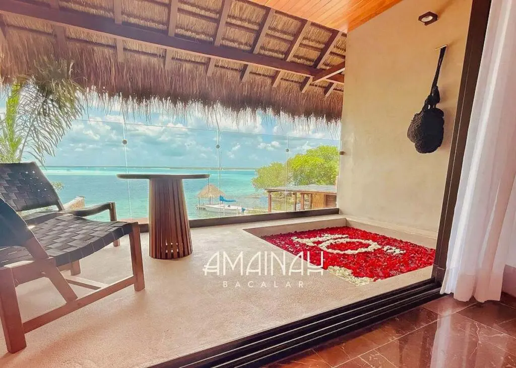 Flowers petals floating in a private pool in a room at Hotel Amainah Bacalar with a view of the a lagoon.