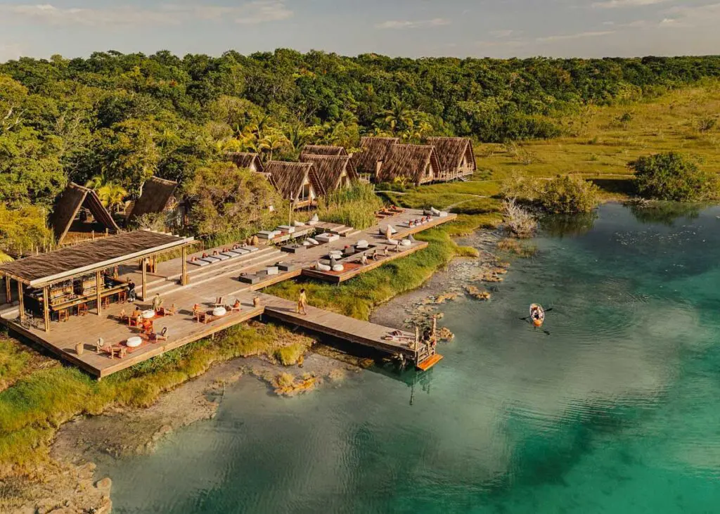 Aerial view of Our Habitas Bacalar on Bacalar lagoon. You can see some of the villas and the dock on the lagoon with lounge chairs and a bar.
