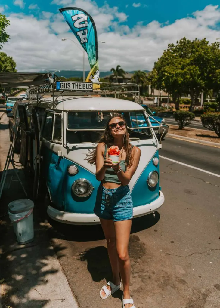 Woman holding shave ice in front of a VW Bus in Kihei, Maui