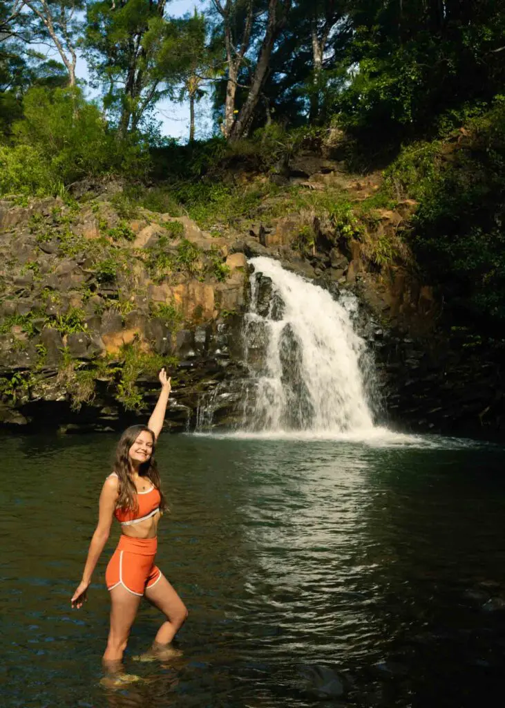 Woman wading in the water at a waterfall on the Road to Hana, one of the best things to do on the Road to Hana!