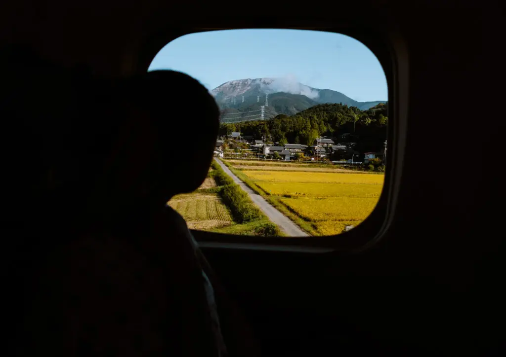 Looking out the window at a mountain in the Japanese countryside on the train