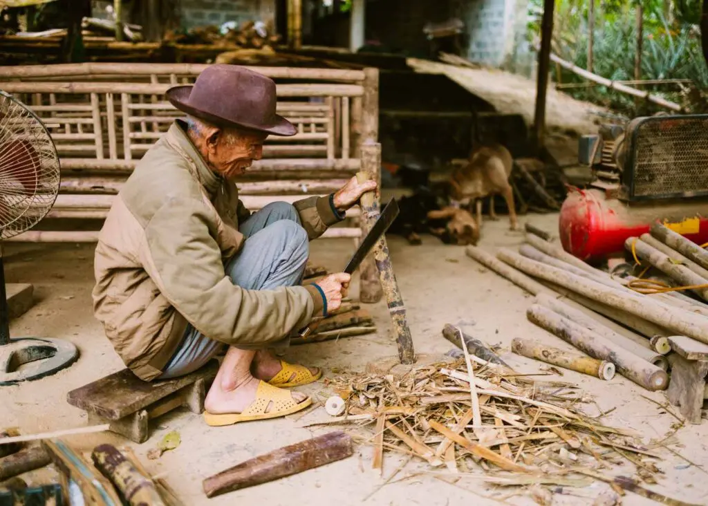 Black thai man chopping wood in a village in Vietnam