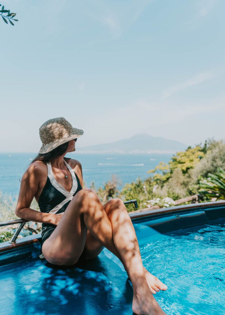 Woman sitting at the edge of pool with Mt. Vesuvius in the backrgound at La Palombara B&B in Vico Equense