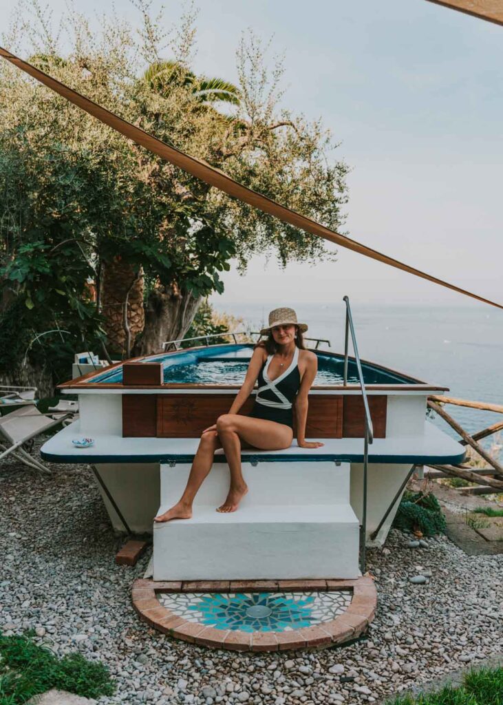Woman sitting in front of boat shaped pool at a B&B in Vico Equense, a lovely place to stay near Sorrento and the Amalfi Coast
