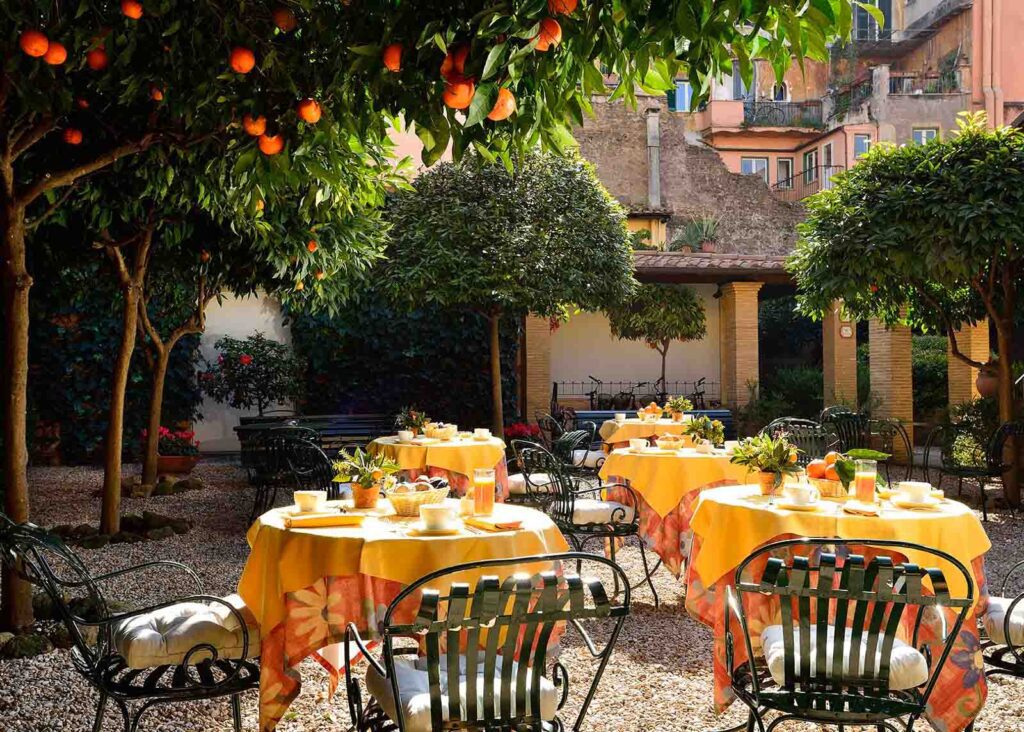 Courtyard inside a Trastevere hotel with orange tree and tables set for breakfast